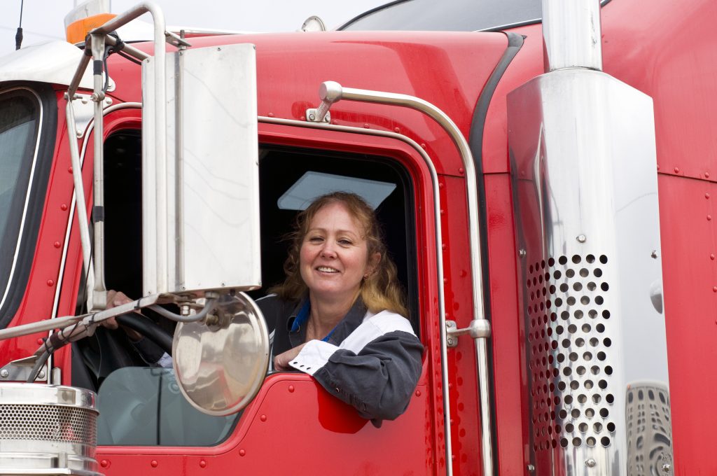 Woman smiles in red semi truck