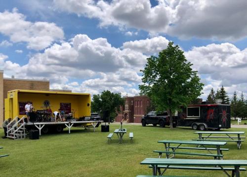 Picnic tables with a food truck and stage for a band